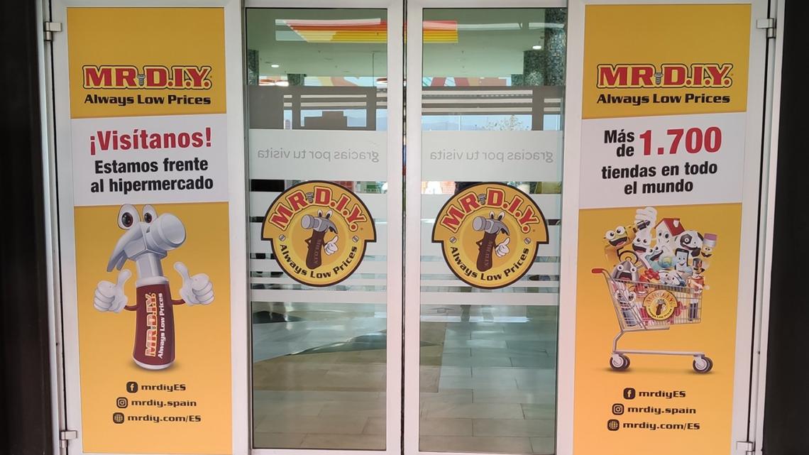 Las puertas de entrada al centro comercial Los Alfares están personalizadas con la imagen de Mr. DIY, para dar a conocer esta nueva tienda a los clientes.